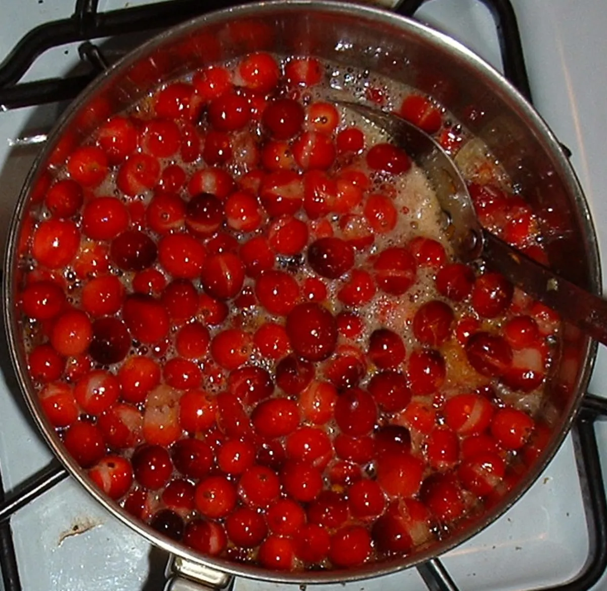 Cranberries simmering on the stovetop into a ruby-red sauce