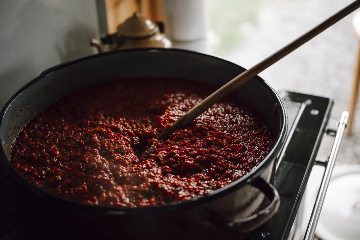 Stirring Thick Tomato Sauce with a Wooden Spoon in a Simmering Pot
