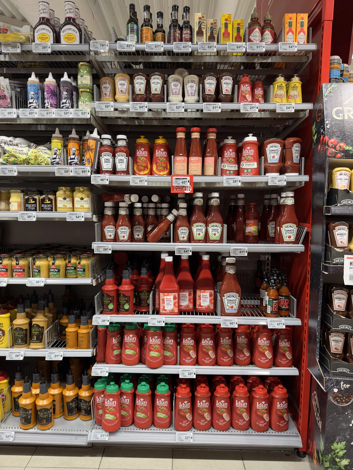 A supermarket condiment aisle stocked with ketchup and sauce varieties